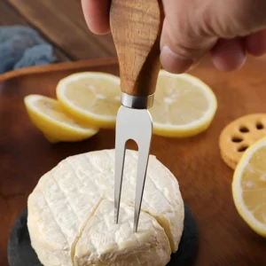 2-tine stainless steel cheese fork with wood handle piercing brie cheese displayed on wooden tabletop, KL-KA-GAD-007.