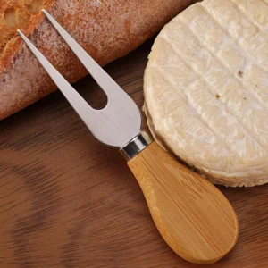 2-tine stainless steel cheese fork with wooden handle next to brie and bread displayed on wooden tabletop, KL-KA-GAD-007.