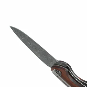 Close-up view of a wave-pattern etched Damascus steel blade on a folding knife, isolated on white background. KL-OD-SS-010