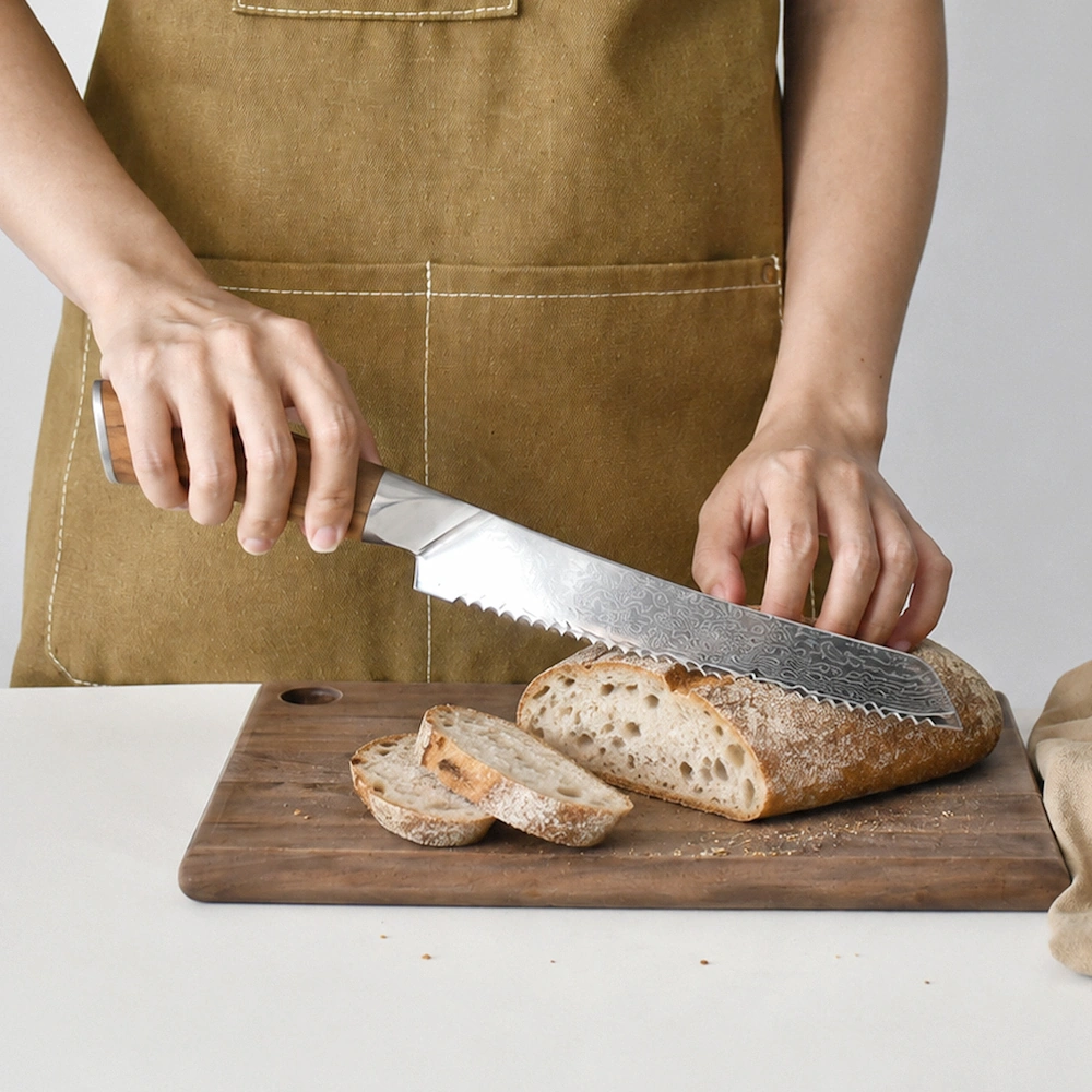 Damascus serrated bread knife being used to slice bread on a cutting board in kitchen environment KL-KN-DS-022