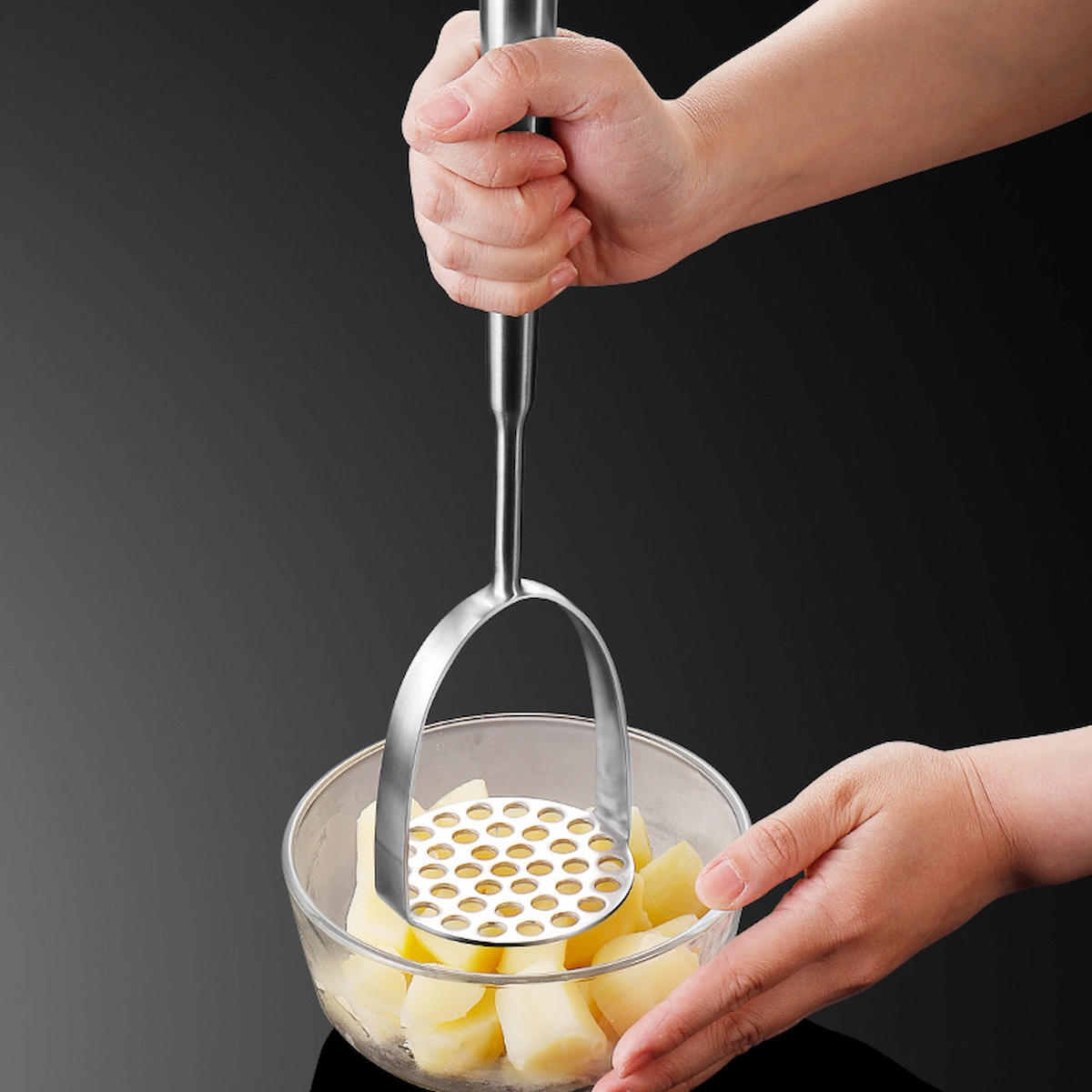 Stainless steel potato masher held in hand for scale while mashing potatoes KL-KA-GAD-001