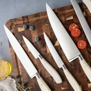 Partial group view of stainless steel kitchen knives with cream white handles displayed on wooden tabletop. SKU: KL-KK-ST-025