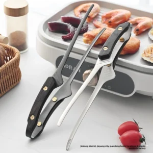 Silver and black matte BBQ carving forks displayed in front of an electric grill with seafood in kitchen environment KL-KA-BBQ-009
