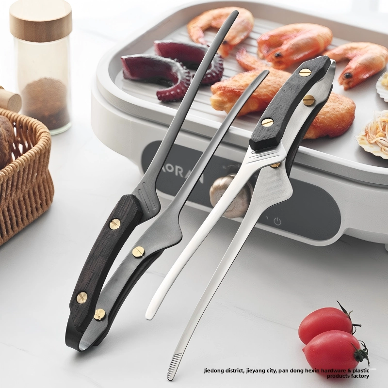 Silver and black matte BBQ carving forks displayed in front of an electric grill with seafood in kitchen environment KL-KA-BBQ-009