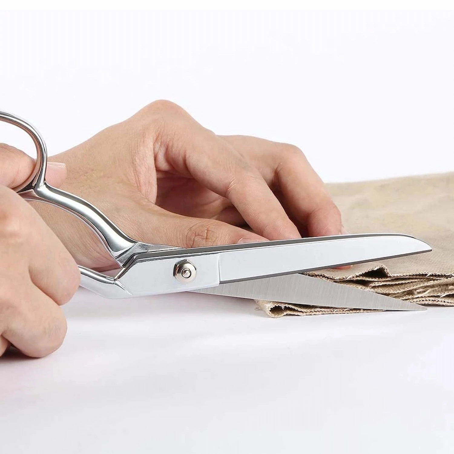 All-metal stainless steel tailor scissors held in hand for scale while cutting brown canvas fabric, SKU: KL-SC-HC-001.