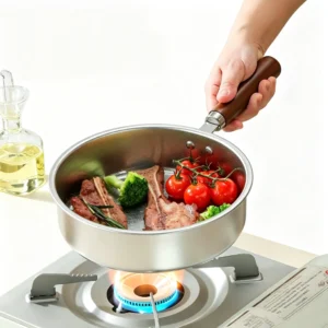Hand holding stainless steel Yukihira saucepan cooking meat and vegetables over a gas stove burner. KL-KA-GAD-030